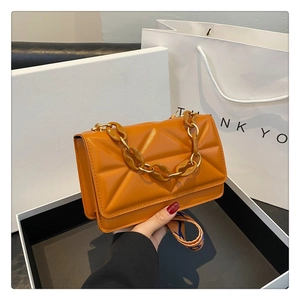 Close-up of orange quilted leather handbag with thick chain handle and woven strap