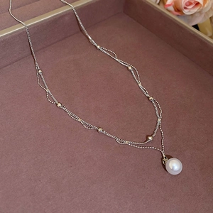 Vue détaillée du collier à double rangée de perles argentées sur un plateau à bijoux