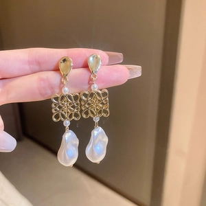 Detailed macro view of baroque pearl drop earring with golden hollow knot design