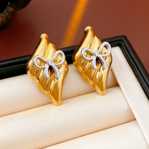 Detail of gold leaf-shaped stud earrings with silver bow accents in jewelry box