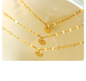 Close-up of triple gold disc necklaces with unique flat hollow link chain displayed on ceramic