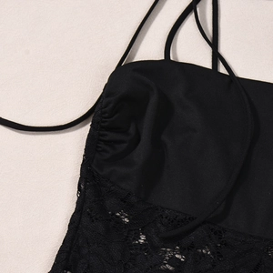 Detail of black camisole showing lace patchwork, thin straps, and pleated chest design