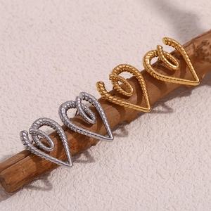 Detail view of gold and silver heart earrings with twisted rope texture on wooden branches
