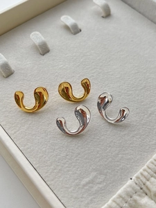 Detailed view of glossy gold and silver U-shaped earrings in a premium jewelry box