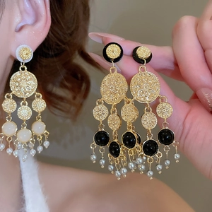Détails rapprochés des boucles d'oreilles rétro avec perles acryliques et glands dorés