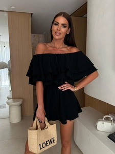 Detail of elegant black off-shoulder ruffled neckline and textured fabric on romper