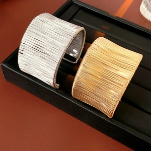Dettaglio di bracciali aperti in oro e argento con trama a filo metallico avvolto