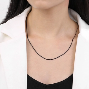 Detailed view of a sleek 1.5mm black snake bone chain necklace worn by a model
