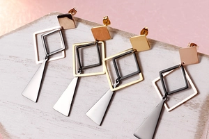 Detailed view of geometric earrings in gold, rose gold, silver and black on stone base