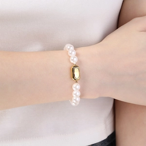 Gros plan d'un élégant bracelet en perles avec fermoir doré sur le poignet du mannequin