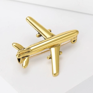 Macro view of a gold airplane brooch with a vintage texture on a white base