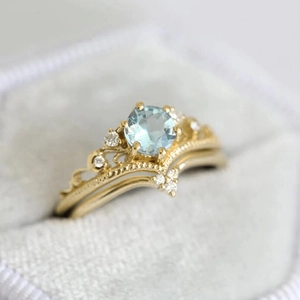 Detailed macro view of two-piece crown ring set with light blue gemstone in jewelry box