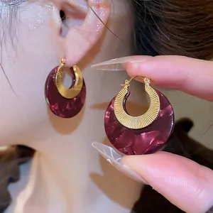 Elegant tortoiseshell resin hoop earrings with gold textured inner ring and red marble finish