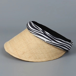 Detail of raffia sun hat with zebra print headband and woven texture for beach vacation