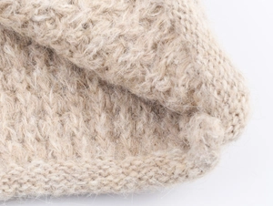 Detailed close-up of beige chunky knit sweater material showing soft wool texture