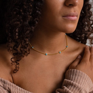 Detail of natural turquoise necklace with gold chain on model neck