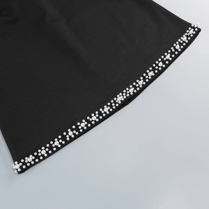 Close-up of elegant white pearls on black fabric of a sexy cutout party dress