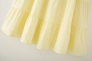 Close-up of the layered ruffle hem and pleated details on a light yellow cotton skirt