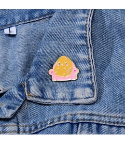 Gros plan d'un badge en métal de pomme de terre dessin animé sur un col de veste en jean