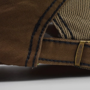 Detail of dark brown canvas beret featuring adjustable bronze buckle and double stitching
