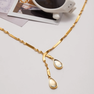 Detail of gold water drop pendants on a mixed flat and twisted link chain necklace