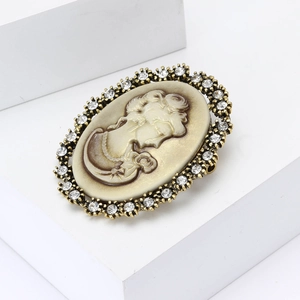 Vintage bronze cameo brooch with sparkling rhinestones on a white geometric stand