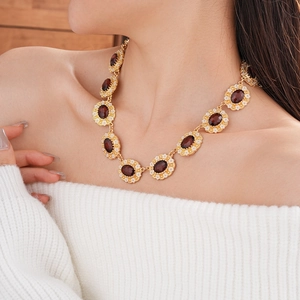 Detail of vintage gold necklace with oval red gemstones and white crystal floral halos