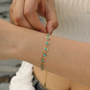 Detail of gold heart bracelet with turquoise stones shown on wrist for styling