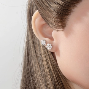 Winter snowflake stud earrings with sparkling diamonds and pearls on female model