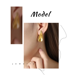 Close-up detail of a golden curved triangular titanium earring on a female model