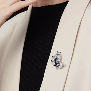Silver butterfly brooch with deep blue crystals on a beige suit lapel for women