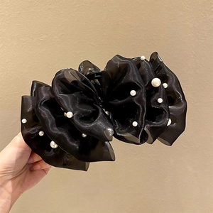 Dettaglio di un fermaglio per capelli in tulle nero con perle bianche in mano