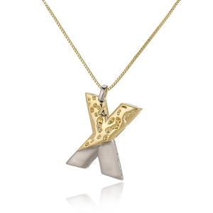 Macro shot of two-tone letter X pendant with hammered gold and smooth silver finish