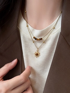 Detail of layered gold sunflower necklace with tiger eye beads on a female model