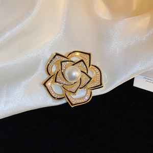 Détail de la broche camélia dorée ornée de perles blanches et de zircons brillants