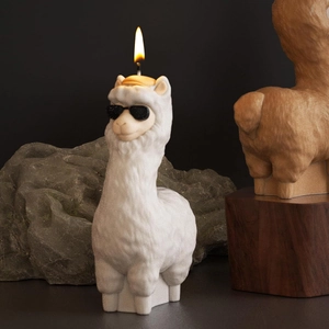 Detail of lit alpaca candle wearing sunglasses on rock base with high contrast lighting
