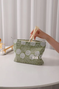 Detail showing hand placing cosmetics into the floral embroidery cotton linen makeup bag
