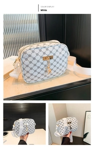 Detail view of white chain-print crossbody bag with golden deer pendant and wide strap