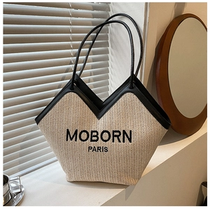 Close-up of woven straw tote bag with black leather trim and MOBORN PARIS embroidery