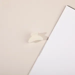 Detail view of a cream white pearl hair claw clip with elegant fan-shaped arc design