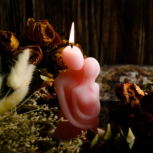 Artistic detail of a couple embrace scented candle lit on a dark wood background