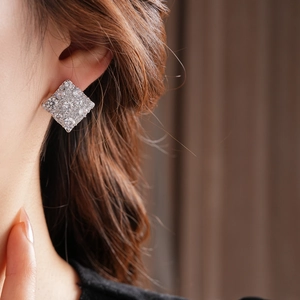 Vue rapprochée de boucles d'oreilles carrées en zircon argenté portées par un modèle