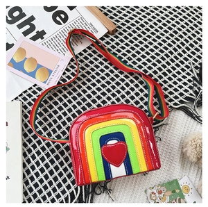 Detail of rainbow-colored semi-circle crossbody bag with red heart patch and striped strap