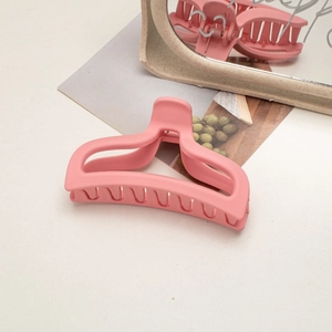 Detail view of a matte pink shark hair claw clip on a stylish white vanity table