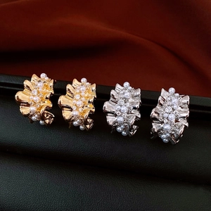 Detailed view of 14k gold and silver pleated C-shaped earrings with pearls and crystals