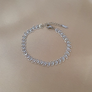Detailed macro view of silver clover leaf chain bracelet with lobster clasp and steel tag
