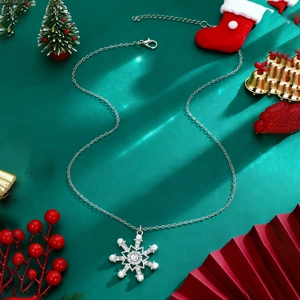 Detail of silver snowflake pendant with pearls and zircons on green background