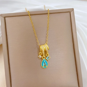 Close-up of luxury gold-plated tassel necklace with blue teardrop crystal and clear diamonds