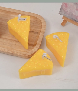 Macro detail of yellow cheese shaped scented candle on wooden tray with creative decor