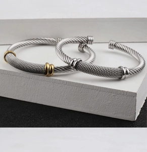 Macro view of mesh weave twisted cable C-shaped cuff bracelets in silver and 18K gold tone